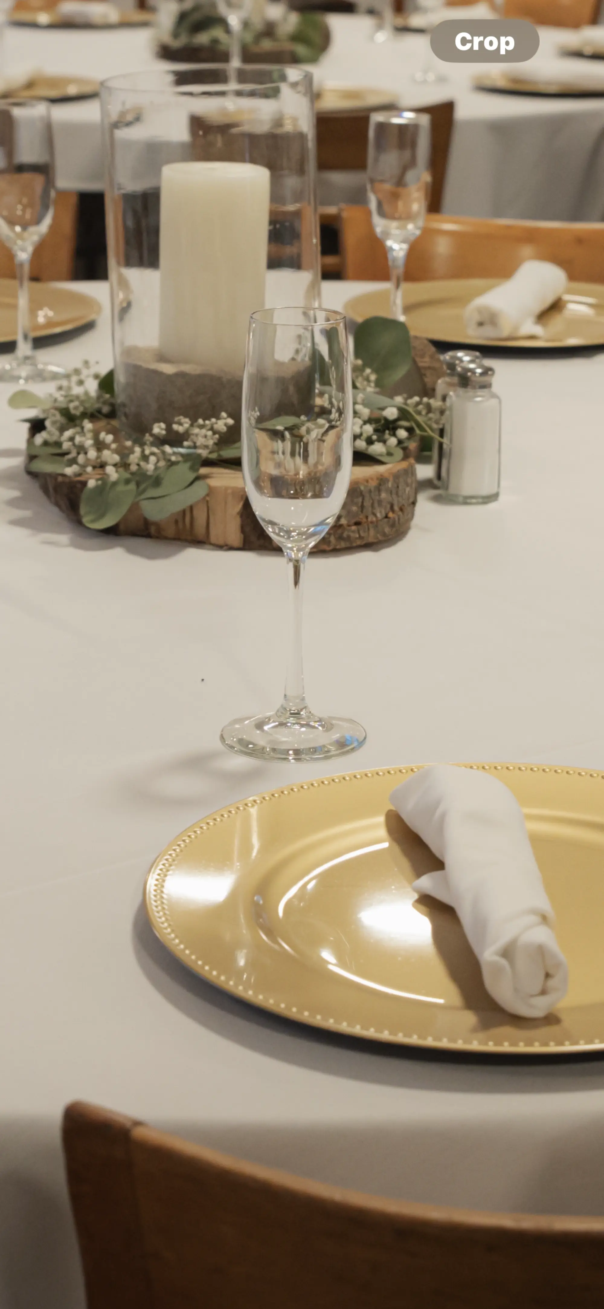 Gold charger plate with white napkin and champagne flute at wedding reception table