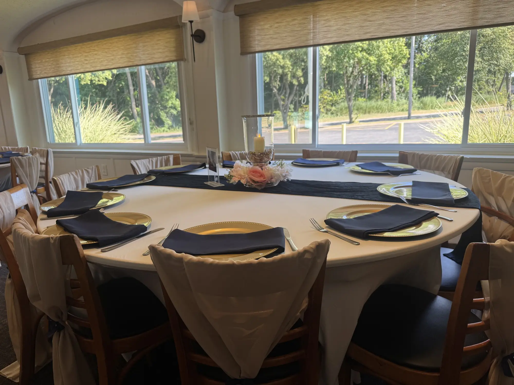 Round table set with gold chargers, black napkins, and floral centerpiece overlooking outdoor venue space