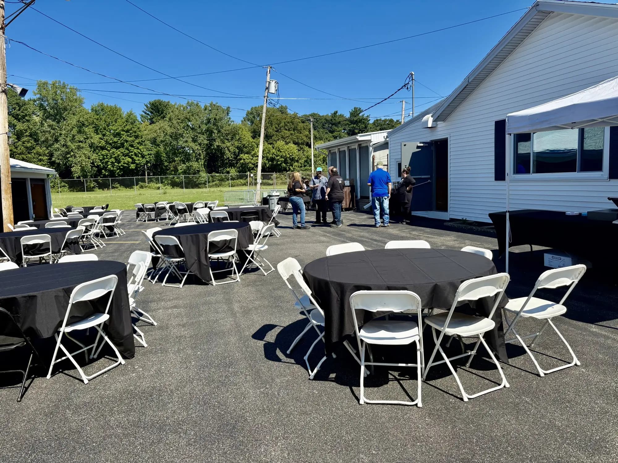 Round tables with black tablecloths and white folding chairs arranged outside Barnard Hall event venue
