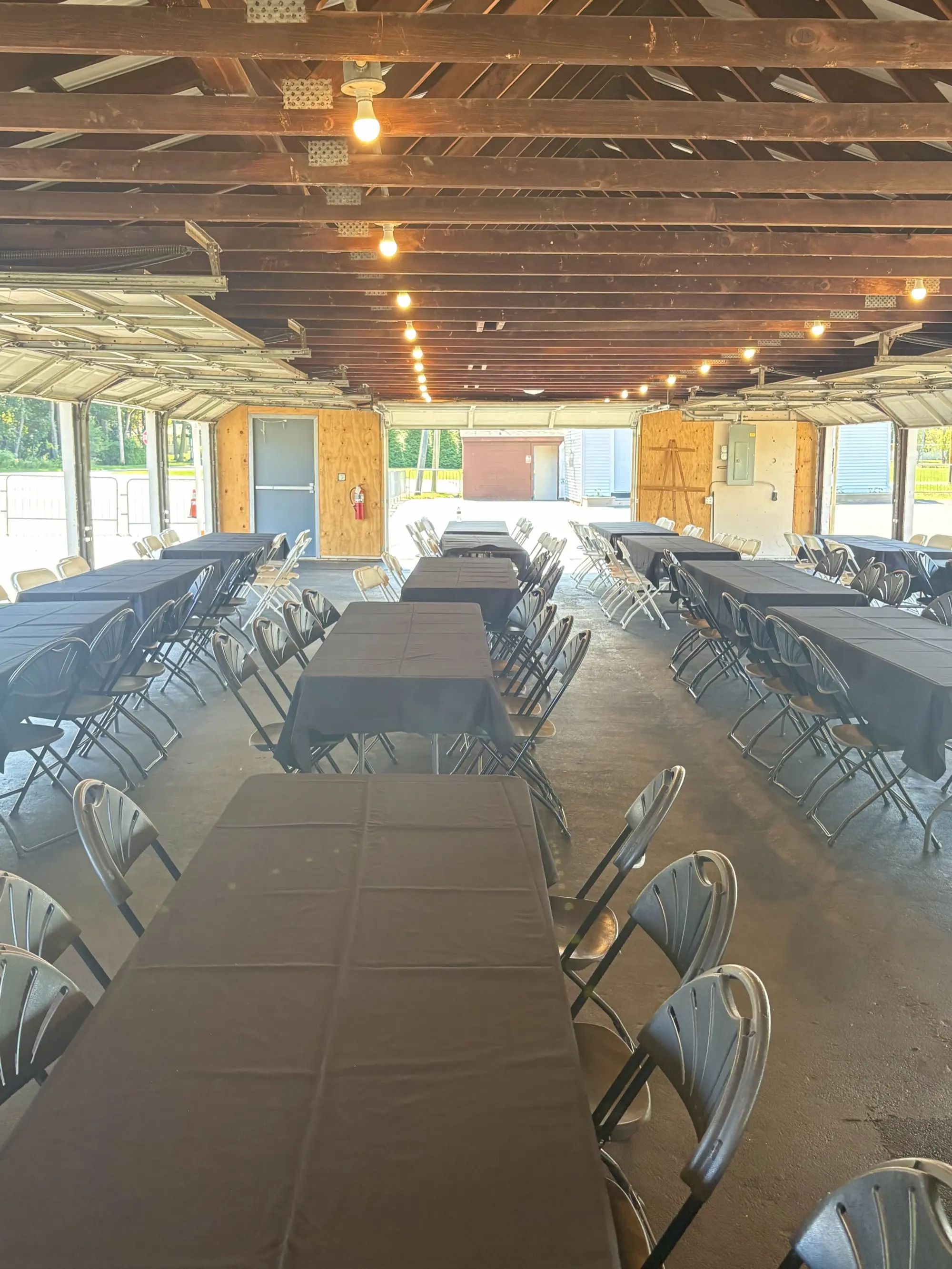 Indoor pavilion with rows of tables set up under exposed wood beam ceiling